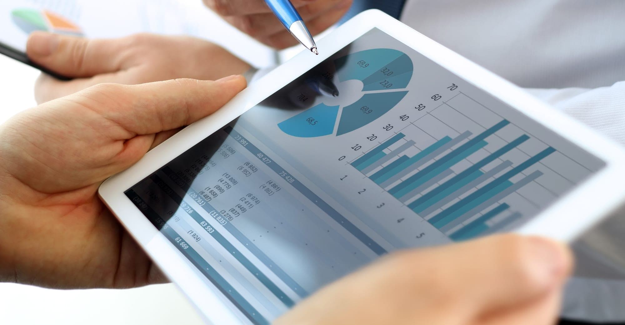 Hands holding a tablet showing business charts